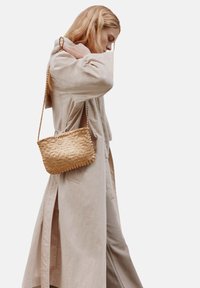 Geweven stro crossbody tas met een rechthoekige vorm en een gestructureerde oppervlakte, voorzien van een gevlochten schouderband en een natuurlijke gouden kleur.