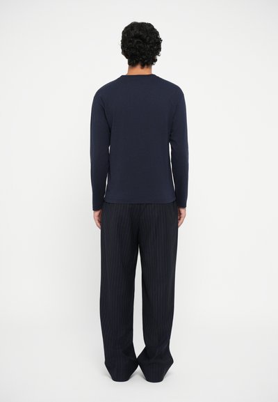 Navy long-sleeve shirt, soft fabric, round neckline, paired with black pinstriped pants, loose fit, subtle texture, straight leg design.