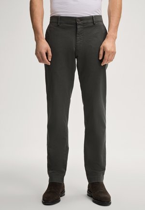 Dunkelgraue Hose aus leichtem Stoff mit Knopfverschluss, Slim-Fit-Design und geraden Beinen. Getragen mit braunen Knöchelstiefeln.