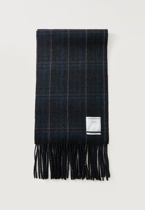 Ciemny wełniany szalik w kratę z frędzlami na końcach i białą metką z napisem "Tiger of Sweden 1903 Made in Italy" na jasnym tle.