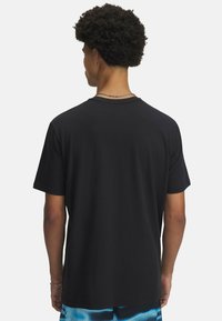 Svart bomulls-t-shirt med korta ärmar, rund halsringning och avslappnad passform. Slät textur, inga synliga mönster eller logotyper. Bakvy.