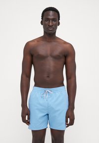 Világoskék fürdőshorts, elasztikus derékkal és húzózsinórral. Sima textúra, térdig érő fazon, és nincsenek látható minták vagy kiemelések.