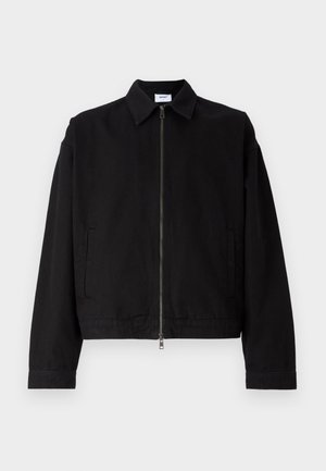 Giacca nera corta in cotone con zip frontale, colletto appuntito e tasche laterali. Presenta maniche lunghe e una texture liscia.