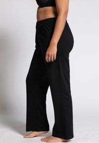 Schwarze Baumwollmix-Hose mit elastischem Bund, geradem Bein und ohne sichtbare Muster oder Hardware, die oberhalb des Knöchels sitzt.