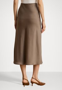 Brun sateng midi-skjørt med en glatt tekstur og en lett glans, med en utsvingt design som går til rett under leggen.