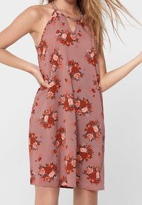 Roze bloemenjurk met halternekontwerp, voorzien van rode en witte bloemenpatronen en een losse pasvorm. Zachte, lichte stof.