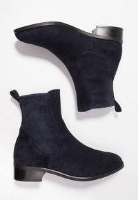Bottines en daim bleu marine avec bout arrondi, panneaux latéraux élastiques, languette de tirage et talon bloc bas avec un accent argenté.
