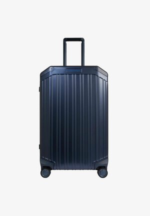 Marineblaue Hartschalenkoffer mit geripptem Design, teleskopischem Griff und vier drehbaren Rädern für einfache Mobilität. Mit einem Logo auf der Vorderseite.