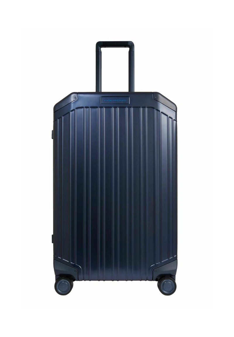 Marineblauwe harde koffer met een geribd ontwerp, uitschuifbare handgreep en vier wieltjes voor gemakkelijke mobiliteit. Voorzien van een logo aan de voorkant.