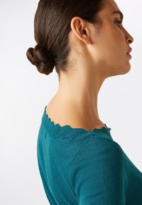 Teal sweater with a scalloped neckline and textured knit detail. The fabric appears soft and close-fitting, showcasing a simple, elegant design.