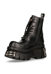 Zwarte leren enkelboot met een dikke platformzool, ronde neus, metalen accenten en een rits aan de zijkant.