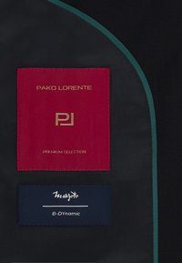 Czarna tkanina z zielonym wykończeniem posiada dwie metki: czerwoną i złotą metkę "Pako Lorente" oraz niebieską metkę "Marzotto B-Dynamic", obie z napisem.