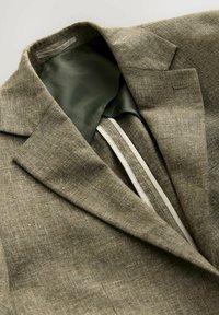 Leinenblazer in erdigem Olivgrün mit glattem Innenfutter und sichtbaren Nähten. Verfügt über einen eingefassten Revers und stilvolle Steppnähte.
