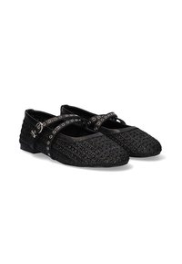 Zapatos planos Mary Jane negros con una textura tejida, con una correa con ojales plateados y un diseño de punta redonda. Tacón plano y bajo.