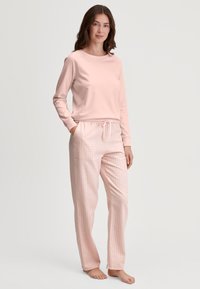 Lichtroze langemouwen top gecombineerd met geblokte roze pyjamabroek met een elastische tailleband en zijkanten. Zachte stof overal.