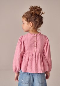 Roze, gestructureerde blouse met lange mouwen, opgeblazen mouwen en een gerimpelde halslijn. Voorzien van een knoopsluiting aan de achterkant en een uitlopende pasvorm.