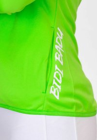 Top sportivo verde neon realizzato in tessuto liscio, con logo "BIDI BADU" bianco sul lato. Design aderente con dettagli di cucitura stilistici.
