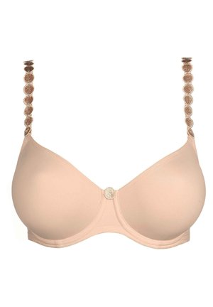 Beige bra with smooth cups and decorative straps featuring circular accents. The center has a small round detailing. Soft fabric texture.
