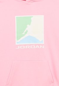 Ροζ φούτερ με κουκούλα από απαλό ύφασμα με λευκό γραφικό ενός άλτη και τη λέξη «JORDAN» με έντονα γράμματα πάνω από την μπροστινή τσέπη.