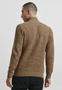 Maglione marrone lavorato a maglia con collo alto e polsini a coste. Presenta un motivo testurizzato e una vestibilità slim.