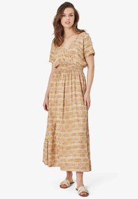 Rochie maxi de culoare maron deschis cu modele geometrice albe. Dispune de mâneci scurte, decolteu în v și talie elastică. Sandale plate.