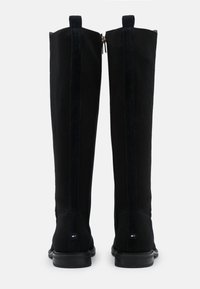 Schwarze kniehohe Stiefel aus geripptem Stoff mit glatten Einsätzen, ausgestattet mit einem Reißverschluss auf der Rückseite und einer flachen Gummisohle.