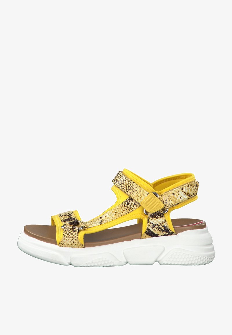 Yellow snake print sandals feature adjustable straps, a padded footbed, and a thick, white rubber sole with textured grip.