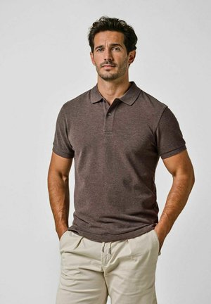 Braunes Polo-Hemd mit kurzen Ärmeln und Kragen, mit glatter Textur. Kombiniert mit hellen Hosen. Einfaches Design, keine Muster.