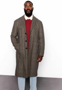 Garšs brunatā un melnā krāsā raibs mētelis ar vienrindas piegriezumu, iegrieztām atlokām un priekšējām kabatām; pārvalkāts uz bordo krāsas augšdaļas.