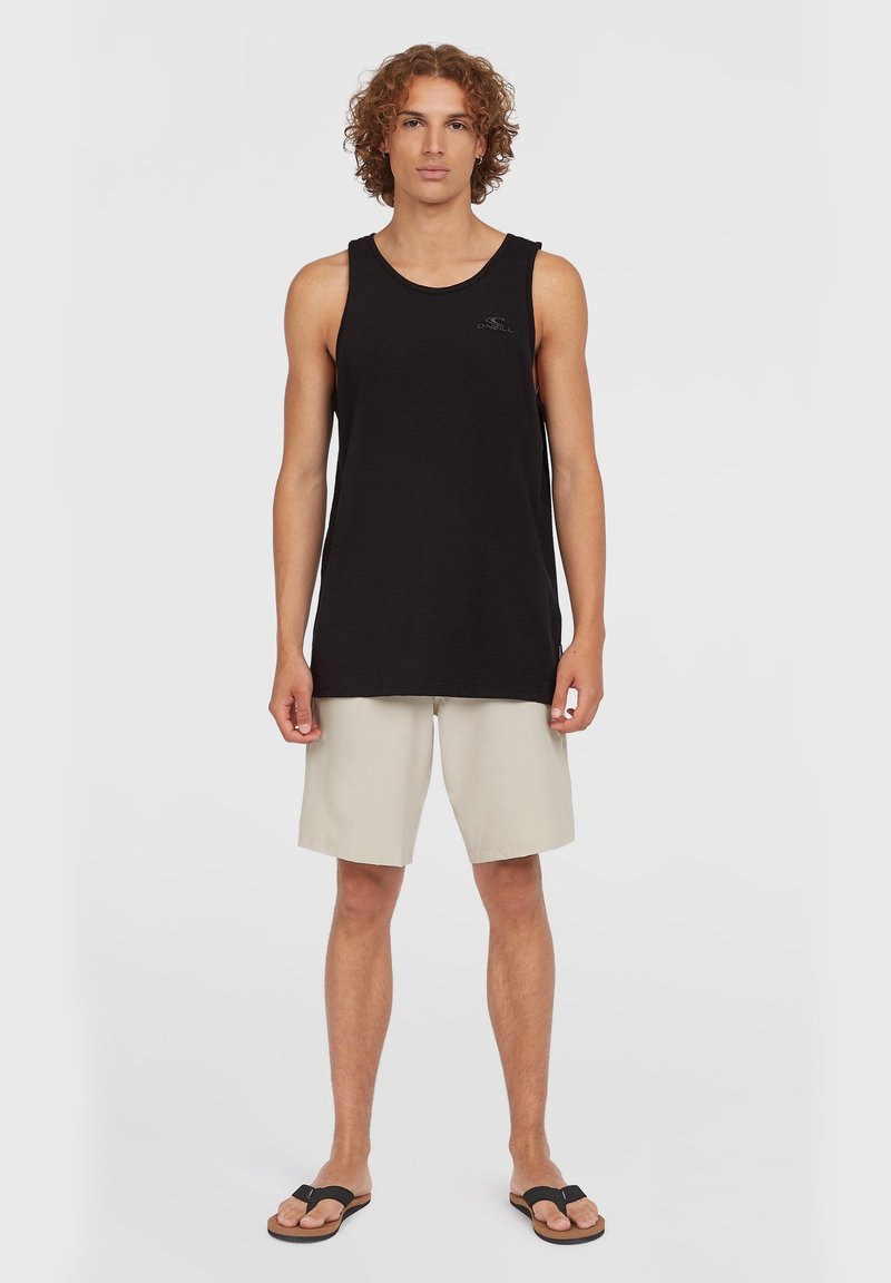 Sort ærmeløs tanktop med rund halsudskæring, lyse beige shorts og brune flip-flops, stående på en ensfarvet hvid baggrund.