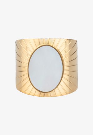 Bracelet manchette en or avec un miroir ovale en son centre et un motif gravé en forme de rayons de soleil rayonnant à partir du miroir.