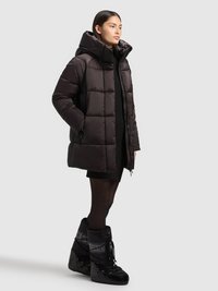 Svart vadderad jacka med stor huva, med quiltad design, sidofickor och kompletterad med snygga svarta vinterstövlar.