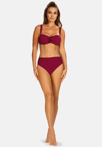 Burgundowy dwuczęściowy kostium kąpielowy z marszczoną górą z kwiatowym akcentem oraz wysokim stanem na dół o gładkiej teksturze i jednolitym kolorze.