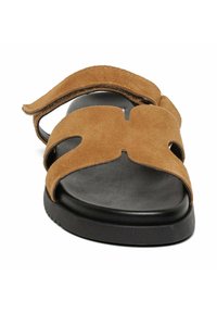 Sandal in suede marrone con design a ritaglio e suola nera. Presenta una fascia ampia sopra il piede e uno stile senza retro per facilitarne l'indossamento e lo sfilamento.