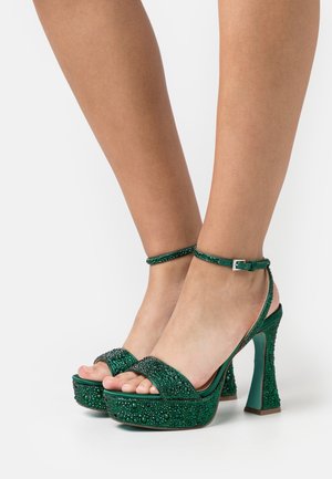 Sandales plateformes vertes avec des embellissements en cristal, bout ouvert et bride de cheville. Elles présentent un talon épais en bloc et un design de surface texturé.