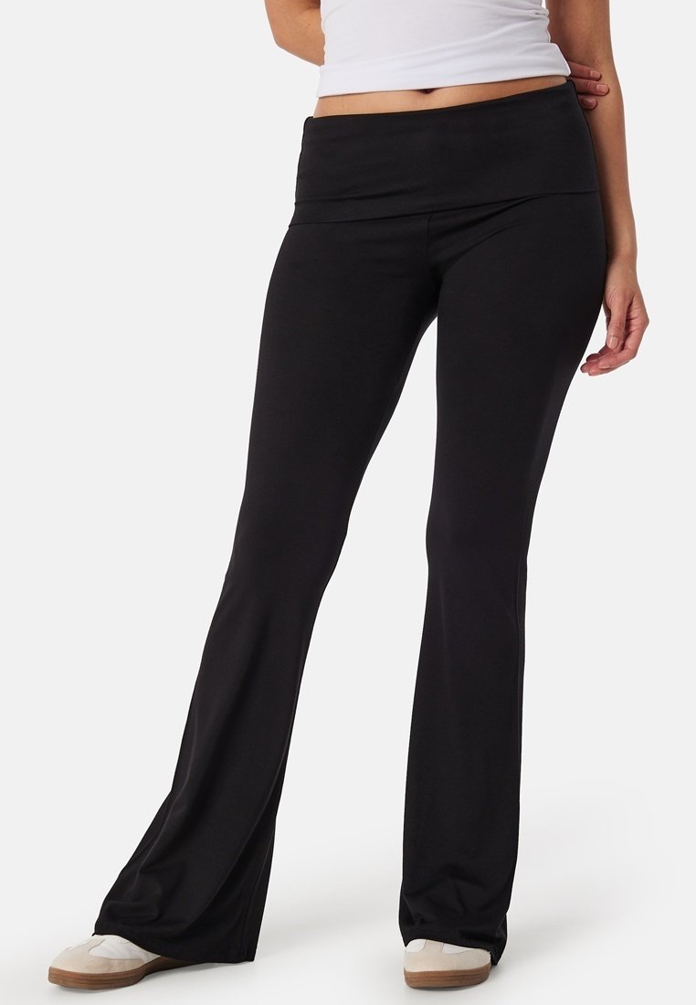Zwarte flared broek van rekbaar materiaal, met een brede tailleband en een gladde textuur. Casual ontwerp geschikt voor verschillende activiteiten.