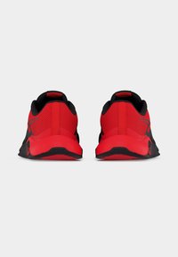 Ζευγάρι αθλητικών παπουτσιών σε κόκκινο και μαύρο, στραμμένα προς τα πίσω, που δείχνουν το πλεκτό επάνω μέρος και την παχιά επένδυση της σόλας σε απλό φόντο.