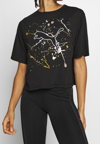 Černé krátké tričko z bavlny s bílou siluetou skákající kočky a barevnými skvrnami ve zlaté a růžové barvě.