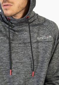 Felpa grigia con cappuccio e un motivo testurizzato, lacci neri con punte rosse e logo "SPYDER" sul petto.