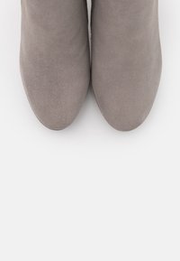 Un par de botas de ante gris fotografiadas desde arriba sobre un fondo blanco, mostrando punteras redondeadas.