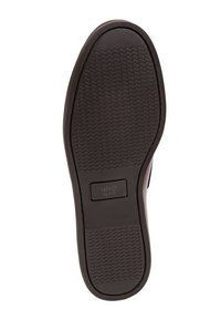 Semelle de chaussure en caoutchouc noir uni avec une surface texturée, présentant un logo rectangulaire encastré et un motif de bande de roulement ondulé pour la traction.