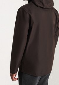 Brązowa wodoszczelna kurtka z kapturem, charakteryzująca się gładką fakturą i minimalistycznym wzornictwem. Brak widocznych zapięć ani wzorów na plecach.