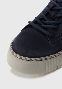 Baskets en daim navy avec un bout rond, une semelle texturée et un détail en bord tressé. Présente des lacets lisses et une languette rembourrée pour le confort.