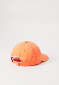 Narancssárga pamut baseball sapka ívelt szélekkel, állítható pánttal hátul és diszkrét varrási részletekkel.