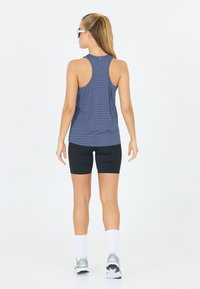 Blauw gestreept sport tanktop met racerback ontwerp, gecombineerd met zwarte fietsbroek. Inclusief witte sportsokken en hardloopschoenen.
