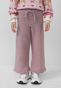 Rosa Fleece-Hosen mit weichem Material, weit geschnitten, und einem verstellbaren Kordelzugbund, kombiniert mit weißen und silbernen Sneakers.