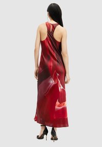 Maxi dress in red and burgundy, made of smooth fabric, featuring a racerback design with abstract patterns and a flowing silhouette.