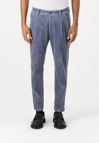 Světle modré manšestrové kalhoty s vertikálními pruhy, s předními záhyby a volným střihem. Nošeny s černou obuví.