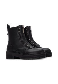Botas de cuero negro hasta el tobillo con acabado texturizado, cremalleras dobles y acentos de ojales. Suela de goma ligeramente elevada y lengüeta en la parte posterior.