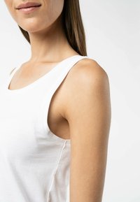 Weißes Baumwoll-Tanktop mit weitem Halsausschnitt und schmalen Trägern, aus glattem Stoff mit taillierter Passform.